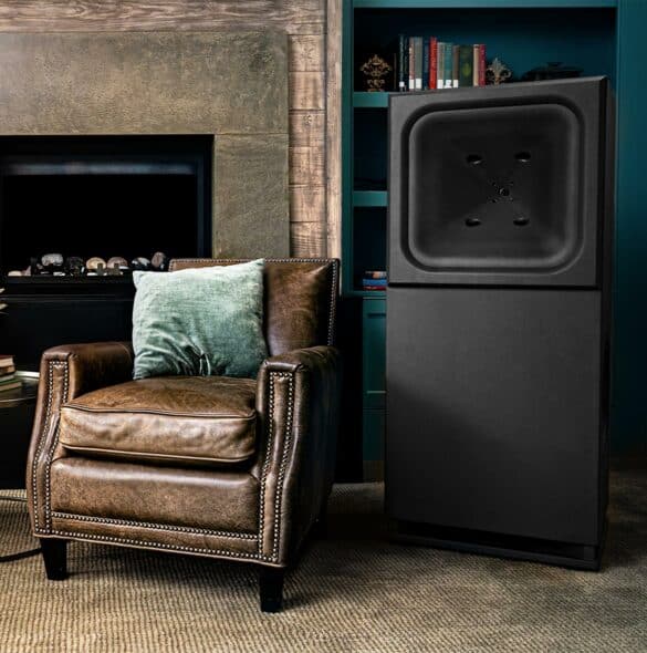 HRE1 loudspeaker beside chair and fireplace